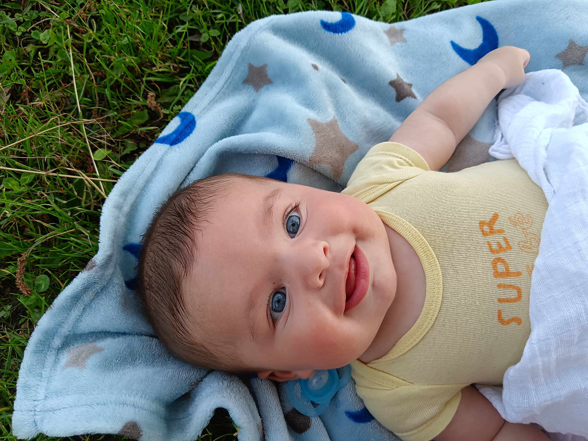 Sohan participe au concours pour gagner de l'argent avec cette photo : baby, blue_eyes, blanket, grass, smiling, infant, pacifier, yellow_clothing, face, outdoor, cute, child, soft_texture, lying_down, happy, nature, toddler, cheeks, portrait, relaxed