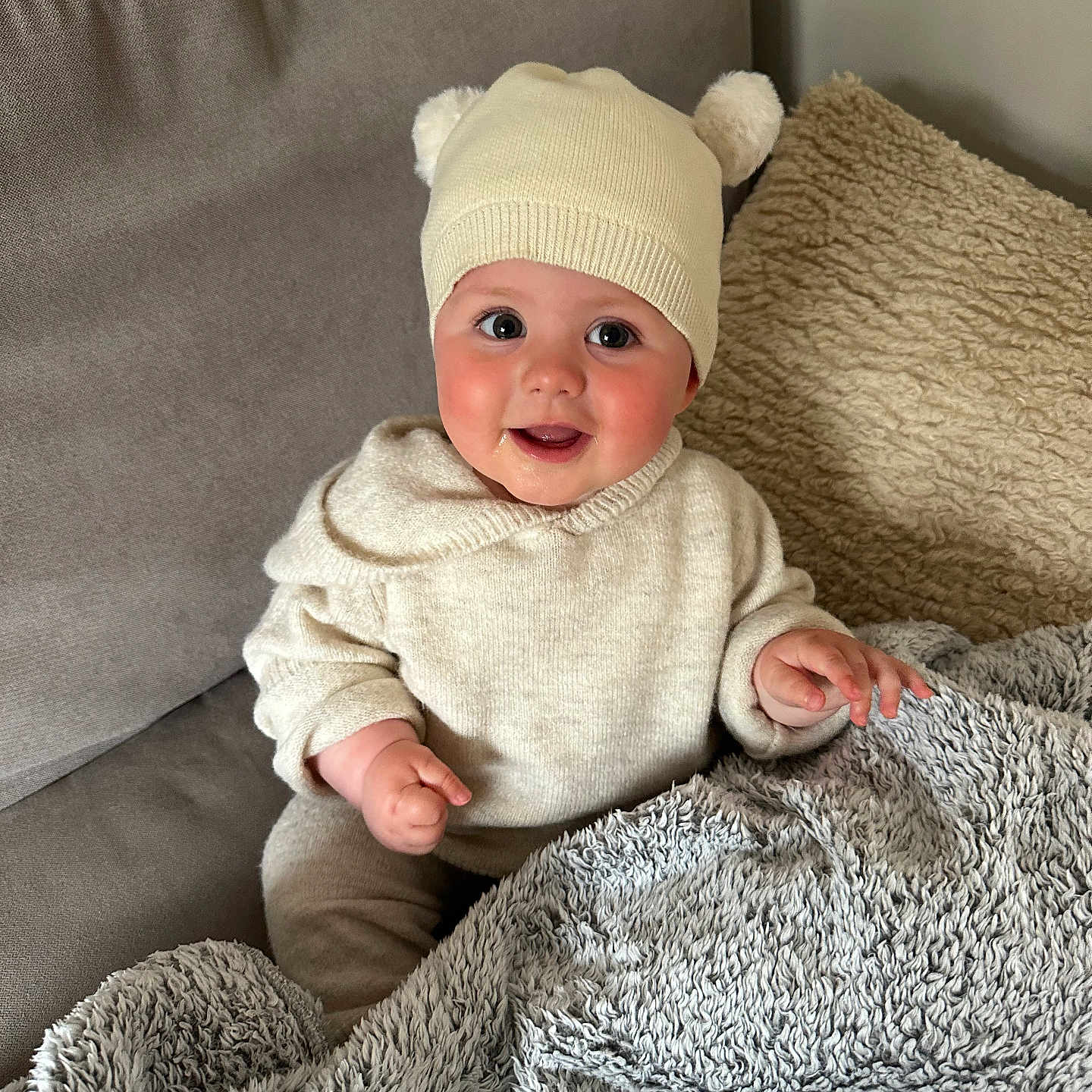 Florence joined the competition — help win amazing prizes! baby, blanket, child, couch, cozy, cute, furniture, happy, hat, home, indoor, infant, person, pom_poms, portrait, seated, smiling, soft_fabric, sweater, warm_clothing