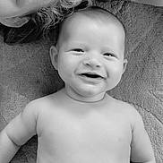Simon participe au concours pour gagner de l'argent avec cette photo : baby, smiling, face, bare_shoulders, blanket, curly_hair, partial_face, black_and_white, portrait, happy, infant, child, closeup, texture, skin, lying_down, cute, expression, soft_light, indoors