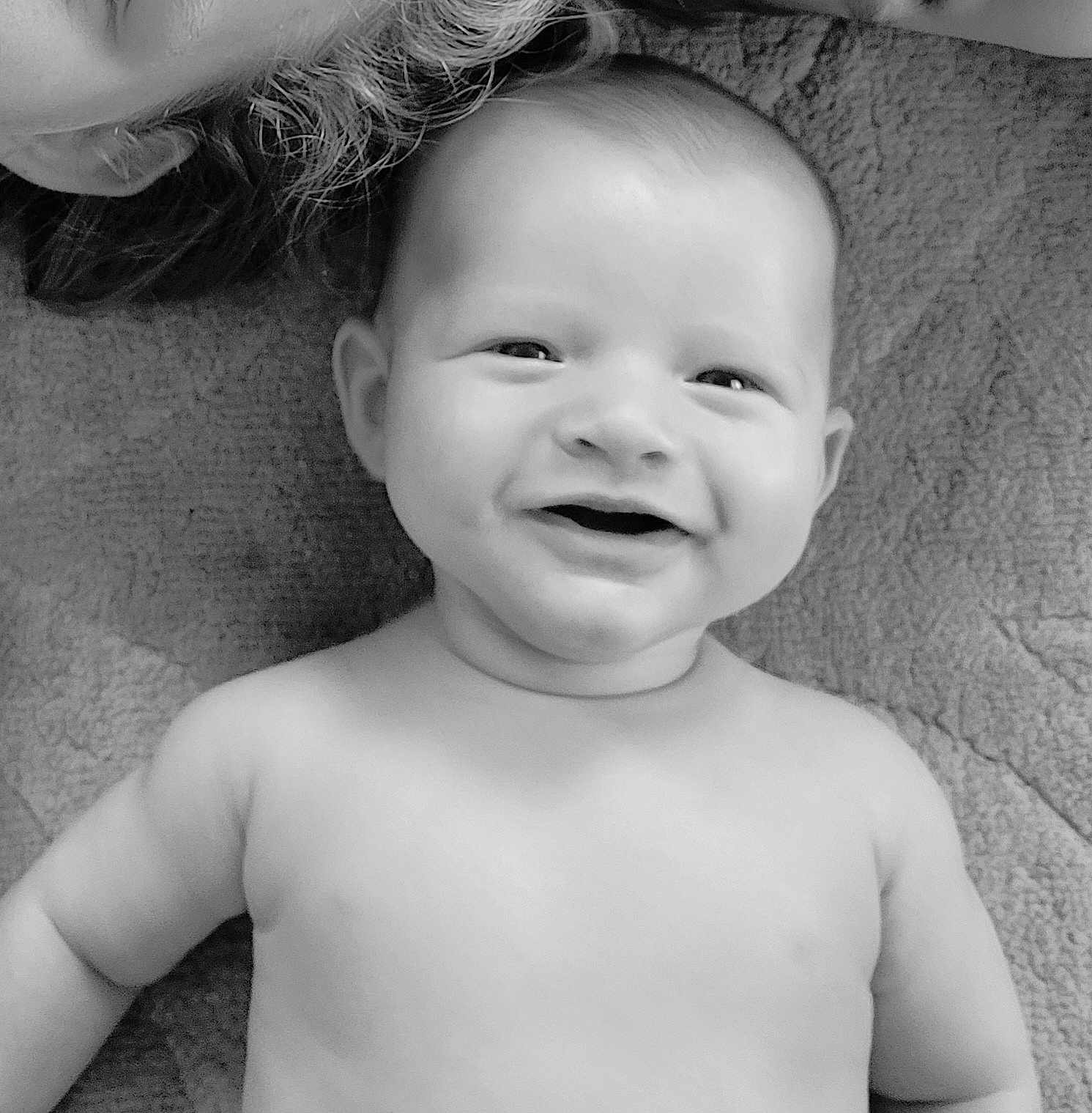 Simon participe au concours pour gagner de l'argent avec cette photo : baby, smiling, face, bare_shoulders, blanket, curly_hair, partial_face, black_and_white, portrait, happy, infant, child, closeup, texture, skin, lying_down, cute, expression, soft_light, indoors