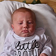 Isaiah joined the competition — help win amazing prizes! baby, infant, child, white_shirt, little_brother, pillow, lying_down, face, expression, indoors, wooden_floor, person, newborn, cute, portrait, clothing, skin, head, young_child, resting