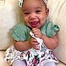 baby, child, smiling, headband, bow, green_top, floral_skirt, lace, sitting, couch, happy, cute, indoors, portrait, young_child, white_tights, furniture, person, infant, dressed_up