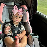 Kalayah is registered to the contest to win money with this photo: baby, child, car_seat, pink_bow, foot, seatbelt, car_interior, window, mesh_screen, clothing, infant, cute, serious_expression, sitting, safety_harness, headband, indoor, person, young_child, portrait