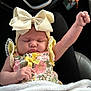 Kalayah is registered to the contest to win money with this photo: baby, infant, child, bow, flowered_clothing, blanket, raised_arm, peaceful, car_seat, sleeping, cute, portrait, hand, headwear, dressed, fingers, soft_texture, indoor, person, expression