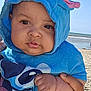 baby, child, blue_towel, hood, beach, ocean, hand, face, portrait, sunny, outdoor, sky, water, sand, cute, expression, person, clothing, closeup, infant
