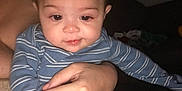 Nathaniel is registered to the contest to win money with this photo: baby, infant, child, person, hand, clothing, onesie, striped_clothing, cute, indoors, portrait, skin, face, eyes, mouth, drool, holding, adult_hand, seated, dim_lighting
