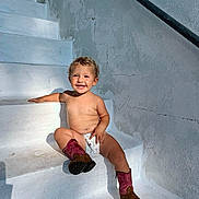 Cameron joined the competition — help win amazing prizes! toddler, child, smiling, stairs, sunlight, outdoor, boots, diaper, bare_chest, happy, cute, playful, white, wall, shadow, curly_hair, young_child, sitting, person, daylight