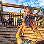 Adrian is registered to the contest to win money with this photo: baby, pacifier, tattoo, adult, outdoor, sky, wooden_deck, blanket, grass, person, smile, playful, holding, sunlight, fence, clothing, happy, child, blue_sky, daytime