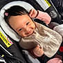 baby, car_seat, smiling, pink_clothing, bib, hair_clip, infant, child, safety_harness, cute, happy, indoors, person, seatbelt, warning_label, closeup, face, young_child, portrait, infant_clothing