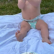 Emerson is registered to the contest to win money with this photo: baby, diaper, birthday_cake, cake, number_one_candle, sprinkles, white_blanket, grass, outdoor, clapping, happy, smiling, celebration, first_birthday, child, person, sitting, nature, greenery, festive