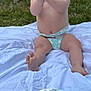 baby, diaper, birthday_cake, cake, number_one_candle, sprinkles, white_blanket, grass, outdoor, clapping, happy, smiling, celebration, first_birthday, child, person, sitting, nature, greenery, festive