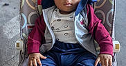 Zayne is registered to the contest to win money with this photo: baby, baby_seat, bouncer, child, clothing, curly_hair, eyes, face, floor, indoor, infant, jacket, pants, patterned_fabric, photography, portrait, serious_expression, shirt, sitting, sneakers