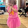 child, girl, pink_clothing, tutu_skirt, socks, dog, dog_bed, living_room, carpet, television, cartoon, laundry_basket, chair, office_chair, furniture, wood_floor, cabinet, smiling, posing, indoors