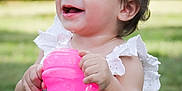Alorah is registered to the contest to win money with this photo: toddler, child, smile, happy, outdoor, grass, pink_sippy_cup, white_dress, baby, cute, drinking, holding, topknot, young_child, sunlight, portrait, nature, daylight, hands, playful