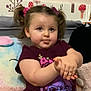 Maya is registered to the contest to win money with this photo: toddler, child, pigtails, purple_shirt, plush_toys, cushions, indoor, cute, smiling, face, hands, seated, home, decor, young_child, expression, person, soft_toys, playful, portrait