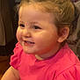 child, toddler, smiling, pink_shirt, toy, indoor, happy, face, hair_tie, cute, rosy_cheeks, person, young_child, playful, sitting, short_sleeves, portrait, baby_toy, closeup, cheerful