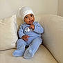 Ilyes a rejoint le concours — aidez-le/la à gagner de superbes lots ! baby, child, infant, blue_outfit, white_hat, couch, sofa, indoor, cute, smiling, portrait, sitting, comfortable, cozy, young_child, person, home, soft_fabric, curious, face