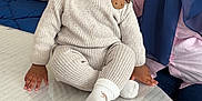 Ilyes a rejoint le concours — aidez-le/la à gagner de superbes lots ! baby, child, infant, knitwear, beanie, table, smartphone, person, adult, blue_hijab, couch, pillow, indoor, seated, curious, wide_eyes, cozy, modern, hands, face