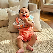 Ayaan is registered to the contest to win money with this photo: baby, smiling, sitting, toy, indoor, pillows, carpet, living_room, child, happy, cute, infant, colorful_clothing, sunlight, cozy, home, floor, person, playful, relaxed