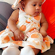 Paris joined the competition — help win amazing prizes! baby, child, dress, hat, orange, couch, cushion, sitting, white_socks, pacifier_clip, cute, indoor, portrait, person, infant, fashion, adorable, skin, face, clothing