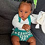 baby, child, infant, sitting, couch, clothing, socks, face, hand, hair, textile, background, green, pattern, indoor, portrait, cute, holding, soft_toy, suspenders