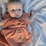 Brielle is registered to the contest to win money with this photo: baby, infant, child, blue_eyes, dress, buttoned_clothing, blanket, soft_texture, curious_expression, laying_down, closeup, portrait, cute, skin, face, small_hands, indoor, comfortable, young_child, apparel
