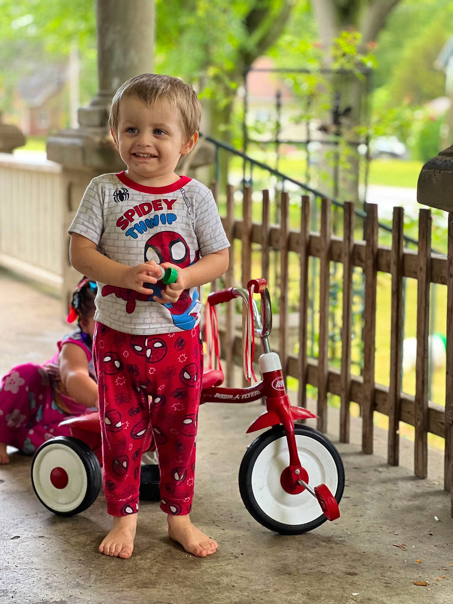 Dean is registered to the contest to win money with this photo: baby_toddler_clothing, bicycle, child, fence, fun, grass, happy, joy, leisure, people_in_nature, person, pink, plant, public_space, recreation, riding_toy, smile, t_shirt, tire, toddler