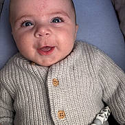 Tommy joined the competition — help win amazing prizes! baby, infant, face, smiling, knitted_sweater, buttons, blue_eyes, toy, cushion, close_up, happy, child, person, portrait, soft_lighting, indoor, cute, newborn, hand, cozy