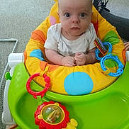 Dougie joined the competition — help win amazing prizes! activity_seat, baby, bright_colors, carpet, child, colorful, comfort, curious, floor, hands, indoor, infant, looking_at_camera, person, plastic_toy, playtime, seat, toy, wide_eyes, young_child