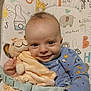 baby, smiling, plush_toy, lion, blue_clothing, baby_mat, animal_print, giraffe, elephant, toddler, cute, child, happy, indoor, soft_toy, infant, face, person, comfort, playtime