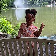 Zabria joined the competition — help win amazing prizes! beads, bench, child, cute, daylight, expression, floral_pattern, girl, greenery, hair_buns, lake, nature, outdoor, pavement, peace_sign, playful, portrait, summer_clothing, trees, water_fountain