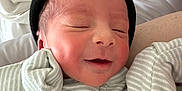 Myles joined the competition — help win amazing prizes! newborn, baby, infant, sleeping, smiling, beanie, striped_pajamas, close_up, face, head, skin, person, cute, resting, peaceful, indoors, blanket, soft, portrait, cozy