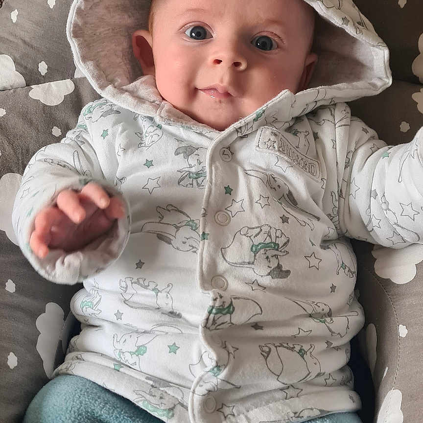 Rhys is registered to the contest to win money with this photo: applique, baby, bed, blanket, bodypart, bonnet, cap, clothing, coat, couch, cradle, crib, cushion, face, finger, fleece, furniture, hand, happy, hat