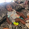 D'Montae joined the competition — help win amazing prizes! baby, infant, bottle, toy, couch, patterned_fabric, indoors, child, clothing, sitting, face, expression, comfort, furniture, hand, foot, room, window_light, blanket, play