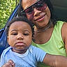 D'Montae joined the competition — help win amazing prizes! baby, woman, child, sunglasses, green_top, blue_outfit, car_door, trees, outdoor, portrait, closeup, person, holding, expression, nature, sunlight, smile, casual, parent, family