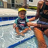 adult, child, family, fun, hand, leg, outdoor, pool, recreation, sitting, skin, smile, splash, summer, sunny, swimsuit, toddler, water, water_reflection, yellow_cap