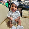 D'Montae is registered to the contest to win money with this photo: baby, child, smiling, sitting, hat, striped_clothing, shoes, couch, cushion, indoor, happy, infant, person, clapping, cute, portrait, casual, comfortable, home, young