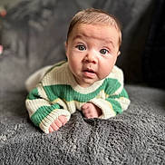 Naël participe au concours pour gagner de l'argent avec cette photo : baby, blanket, closeup, couch, curiosity, cute, expression, eyes, face, gaze, green_sweater, hands, indoors, infant, knitwear, plush, portrait, soft_texture, striped_clothing, tummy_time
