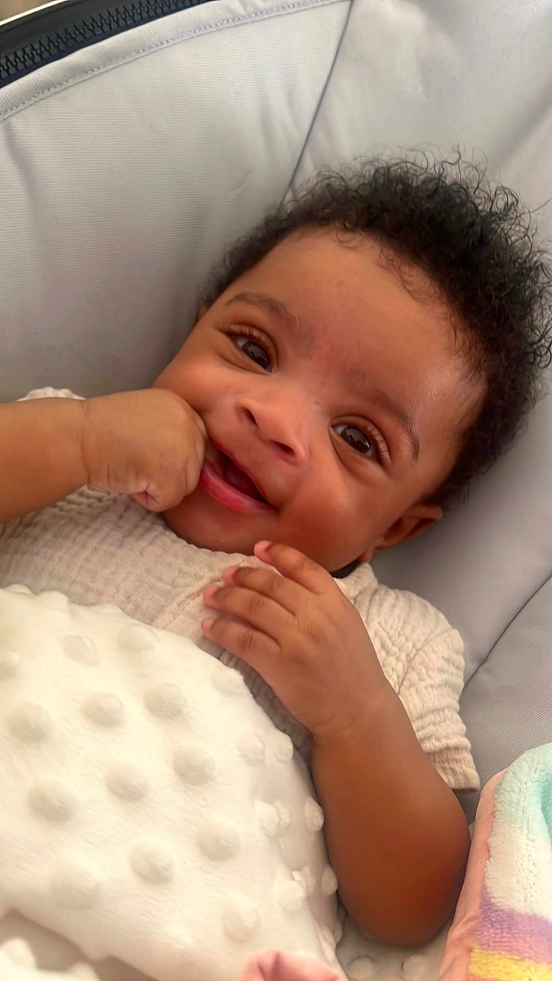 Deaudriee is registered to the contest to win money with this photo: baby, smiling, curly_hair, blanket, cushion, infant, hand, clothing, face, cute, comfort, portrait, indoor, soft_texture, happy, child, skin, expression, closeup, relax