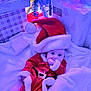 Rowan is registered to the contest to win money with this photo: baby, christmas, holiday, santa_hat, santa_costume, gift, present, tree, christmas_tree, lights, blanket, holiday_decor, infant, festive, cute, indoors, celebration, child, smiling, cozy