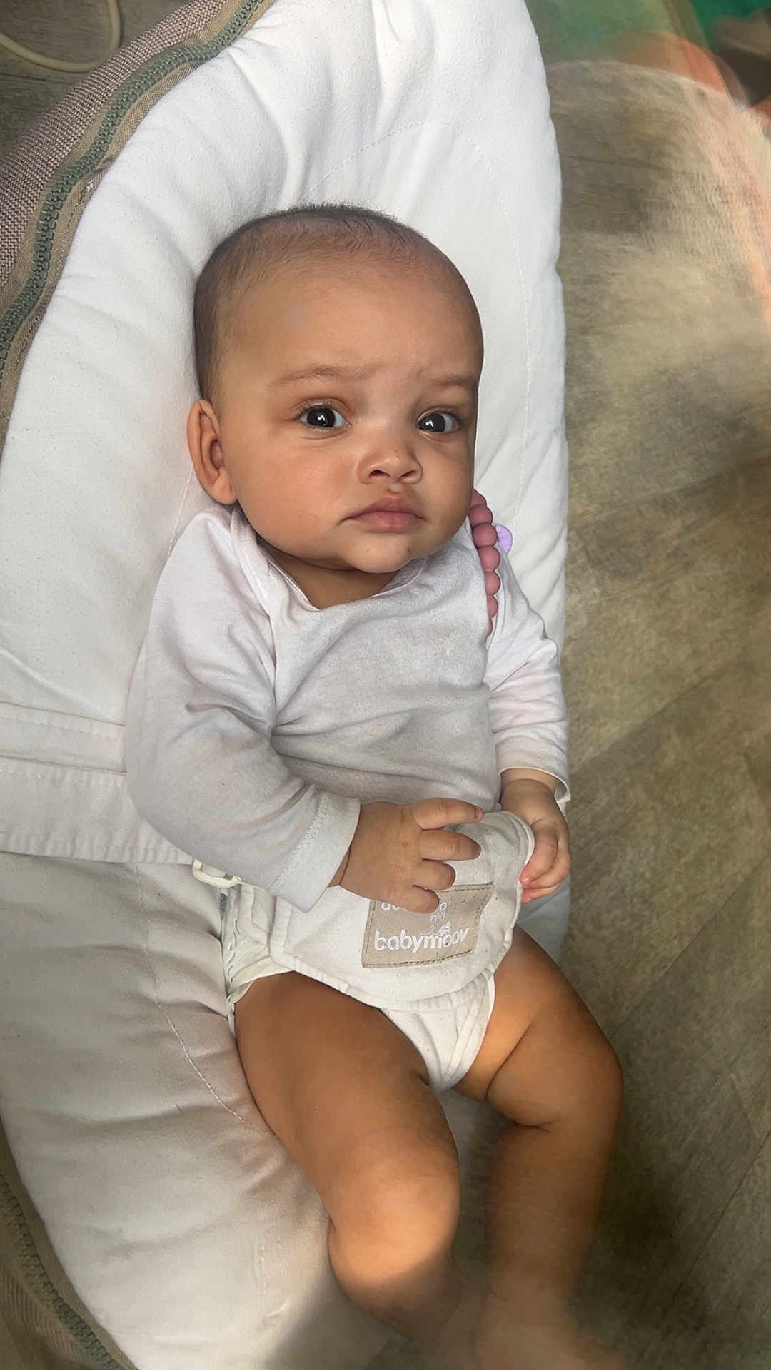 Sheryfa participe au concours pour gagner de l'argent avec cette photo : baby, infant, child, bouncer, onesie, bib, pillow, skin, legs, hands, eyes, serious_expression, dark_eyes, indoor, wooden_floor, beads, teether, portrait, sitting, cute