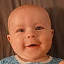 baby, child, smile, face, onesie, elephant_pattern, blue_clothing, infant, happy, lying_down, closeup, cute, skin, head, eyes, mouth, indoors, soft_surface, background, portrait