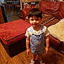 Isaiah is registered to the contest to win money with this photo: child, toddler, indoor, living_room, overalls, sandals, dinosaur_print, carpet, sofa, pillow, ottoman, wood_floor, table, chair, handbag, window, curtains, person, smile, furniture