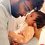 baby, man, glasses, beard, holding, face, love, intimacy, closeup, indoor, sweater, heart_pattern, child, parent, affection, portrait, person, warm_light, cuddling, family