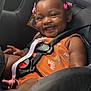 baby, child, car_seat, smiling, happy, hair_clips, orange_clothing, seatbelt, infant, cute, safety, car_interior, portrait, young_child, child_safety, baby_girl, seat, straps, fun, joyful