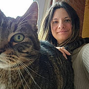 Vanille participe au concours pour gagner de l'argent avec cette photo : cat, tabby_cat, woman, person, indoor, close_up, face, smile, fur, whiskers, hand, hair, window, brick_wall, sweater, pet, animal, domestic_animal, portrait, cozy