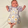 baby, infant, smile, face, clothing, purple, daisy_pattern, overalls, shorts, lying_down, white_background, cute, happy, child, soft_light, skin, hands, feet, portrait, young