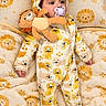 baby, child, infant, portrait, lying_down, pacifier, plush_toy, stuffed_animal, onesie, hooded_outfit, lion_pattern, blanket, bedding, cozy, indoor, nursery, wide_eyed, cute, soft_toys, photography
