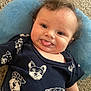 baby, blue_cushion, carpet, child, closeup, clothing, curly_hair, cute, dog_print, funny_face, happy, indoor, infant, navy_shirt, person, playful, portrait, resting, smiling, tongue_out