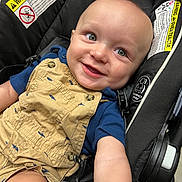 Theo joined the competition — help win amazing prizes! baby, child, smiling, car_seat, overalls, blue_shirt, baby_bottle, face, eyes, arm, clothing, seatbelt, warning_label, infant, cute, safety, indoor, person, portrait, happy